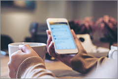 woman with a cup of coffee in one hand and a cell phone in the other