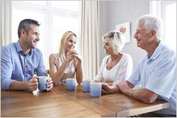 Elderly couple and younger couple sitting at a table having coffee