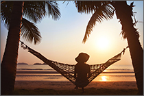 Woman relaxing in hammock at sunset on the beach