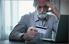 Elderly man looking concerned looking at credit card