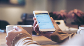 Woman holding cell phone and coffee