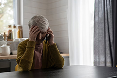 Elder woman on phone with hand to head